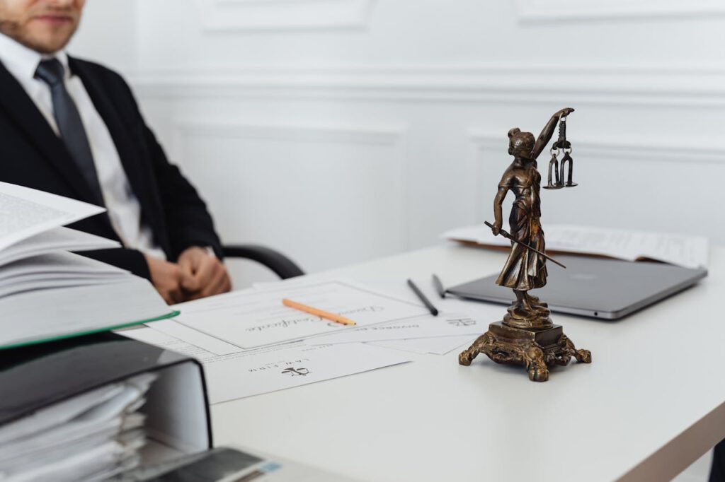 A legal professionals workspace featuring Lady Justice statue, documents, and a laptop.